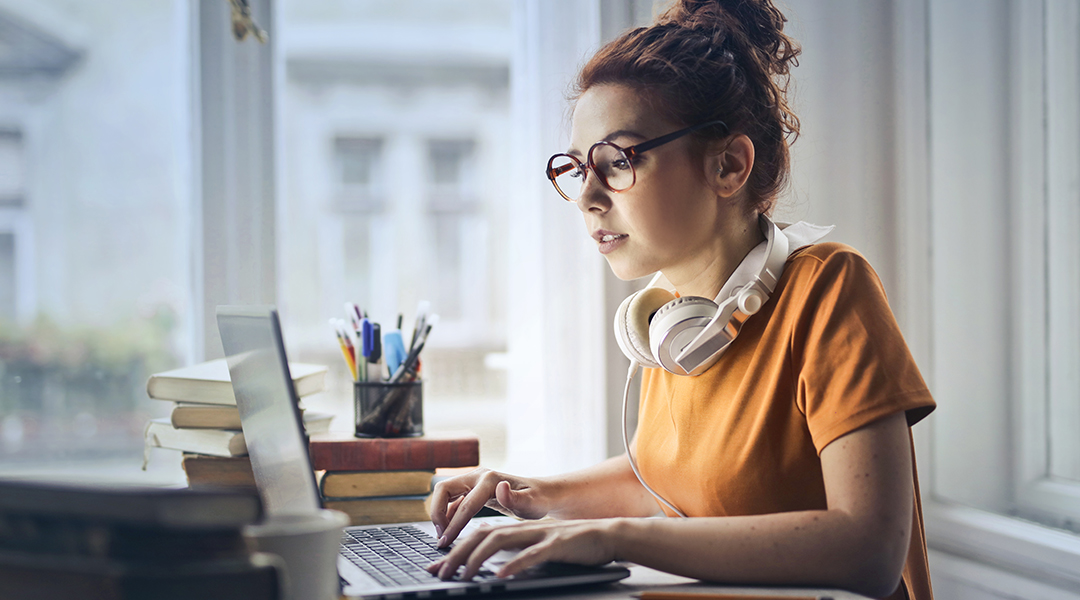 Young girl with headphones working on a laptop